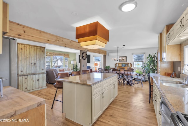 kitchen with light wood-style flooring, a sink, open floor plan, stainless steel appliances, and a breakfast bar area