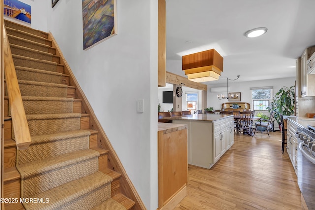 stairway featuring baseboards, a notable chandelier, and wood finished floors