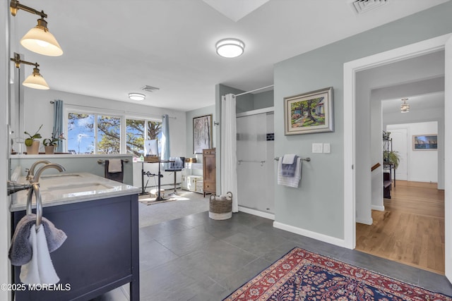 bathroom featuring vanity, a shower stall, baseboards, and visible vents