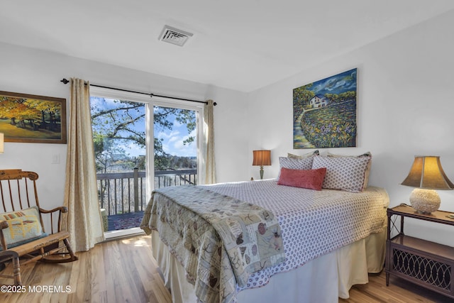 bedroom with visible vents, wood finished floors, and access to outside