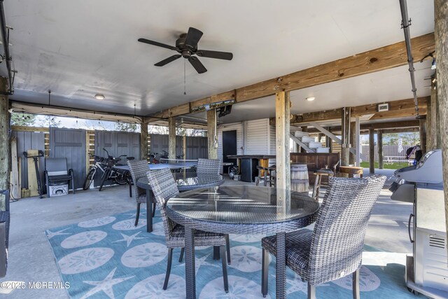 view of patio featuring outdoor dining area, ceiling fan, and fence