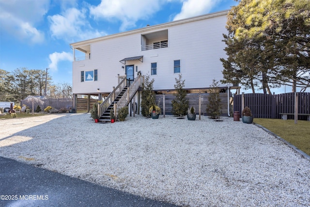 rear view of house featuring a carport, stairway, driveway, and fence