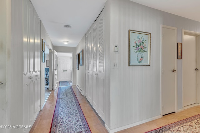 hallway with visible vents and baseboards