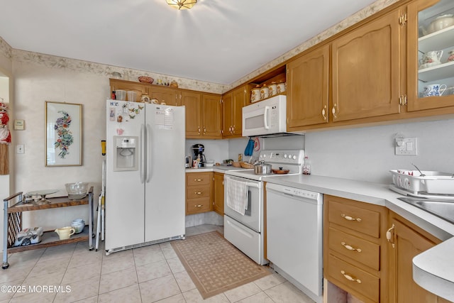 kitchen featuring glass insert cabinets, white appliances, light countertops, and light tile patterned flooring