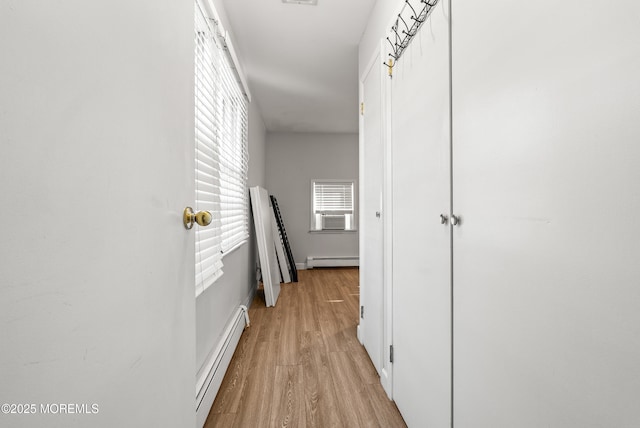 hallway with a baseboard heating unit, light wood-style flooring, and baseboards