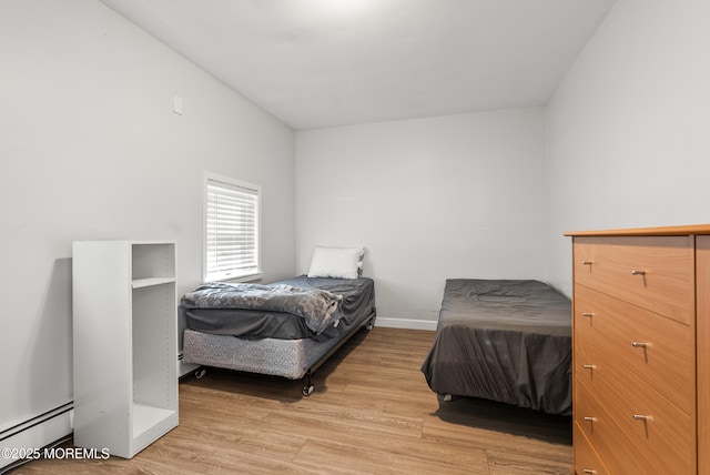 bedroom with light wood finished floors, a baseboard radiator, and baseboards