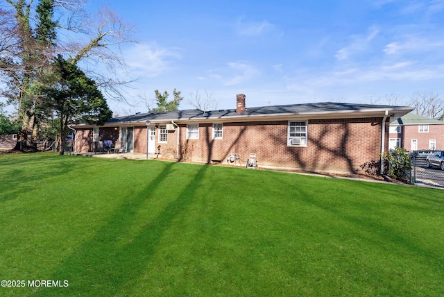 back of house featuring a patio area, brick siding, a yard, and a chimney