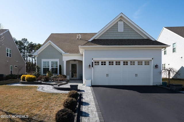 view of front facade with a garage, aphalt driveway, roof with shingles, and a front yard