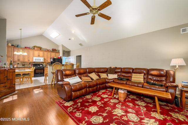 living room featuring ceiling fan, high vaulted ceiling, visible vents, and light wood-style floors