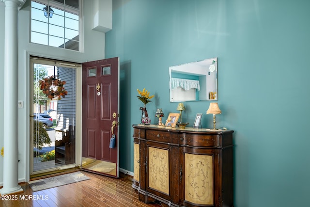 entryway with decorative columns, a high ceiling, baseboards, and hardwood / wood-style floors