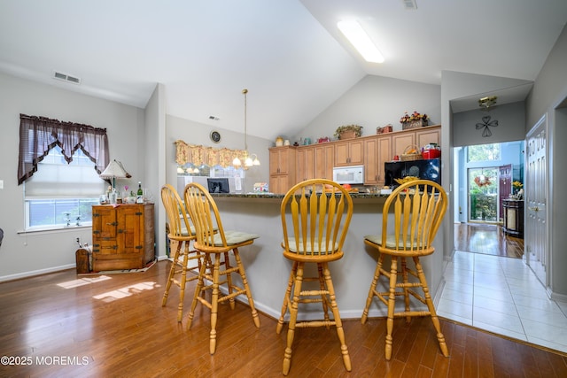 kitchen with white microwave, fridge, visible vents, and a wealth of natural light