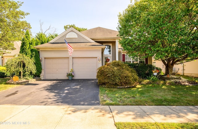 view of front facade with an attached garage, aphalt driveway, and a front yard