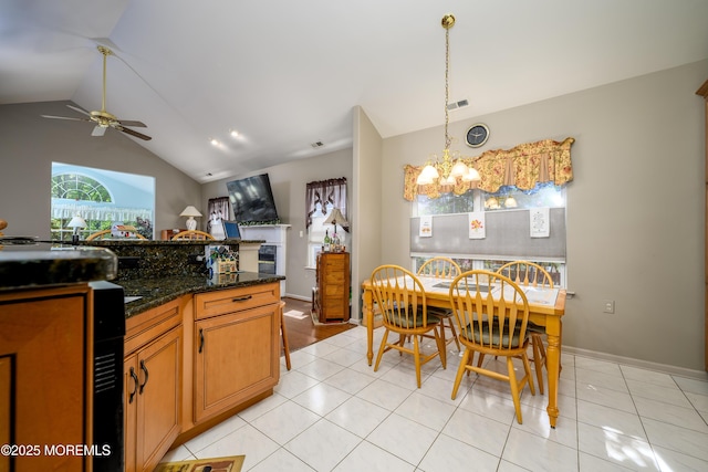 kitchen featuring lofted ceiling, light tile patterned floors, ceiling fan with notable chandelier, visible vents, and hanging light fixtures