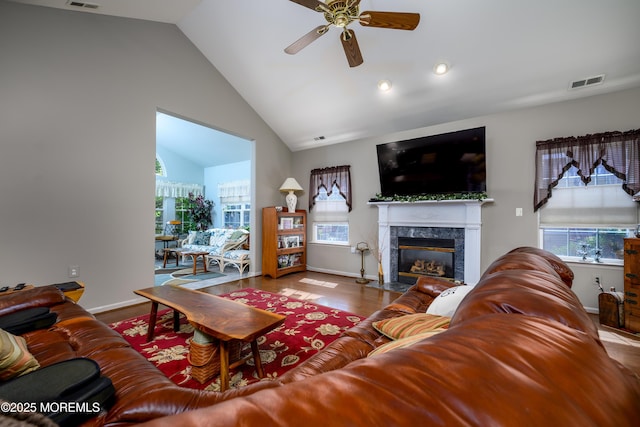 living area featuring ceiling fan, wood finished floors, visible vents, baseboards, and a high end fireplace