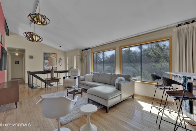 living area with plenty of natural light, lofted ceiling, and hardwood / wood-style floors