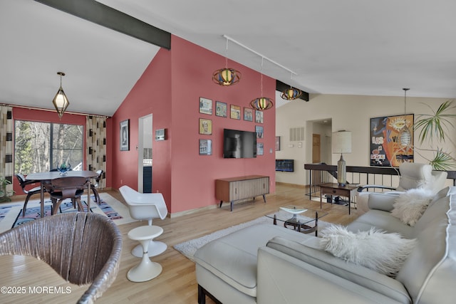 living area featuring visible vents, lofted ceiling with beams, baseboards, and wood finished floors