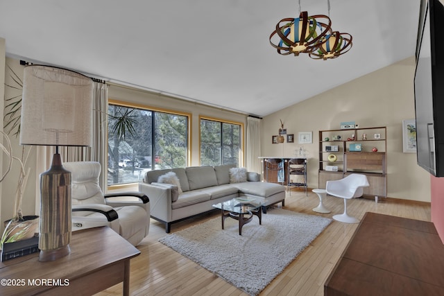 living room featuring light wood-type flooring, a notable chandelier, and vaulted ceiling