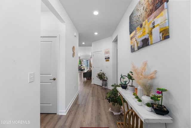 corridor with baseboards, wood finished floors, and recessed lighting