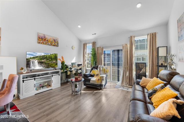 living room with high vaulted ceiling, wood finished floors, visible vents, and recessed lighting