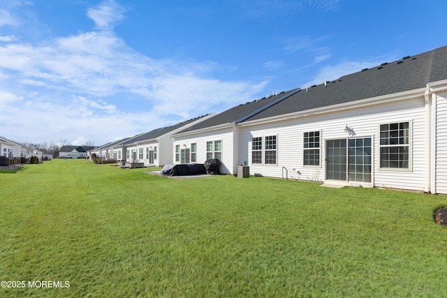 rear view of property with a lawn and roof with shingles