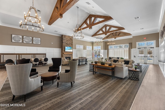 living room with high vaulted ceiling, a stone fireplace, french doors, wainscoting, and beam ceiling