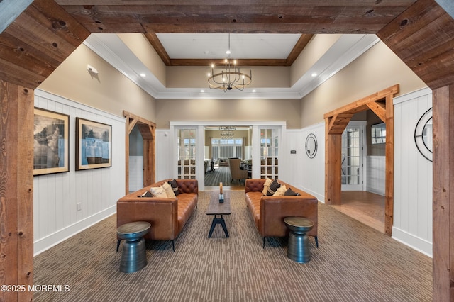 carpeted living area with ornamental molding, french doors, a notable chandelier, and beamed ceiling