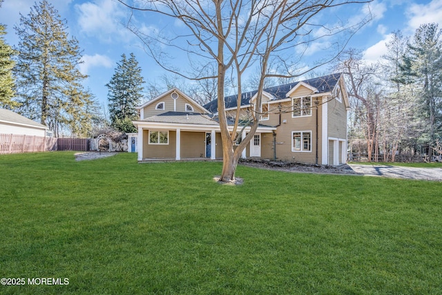 view of front of house featuring aphalt driveway, a front yard, and fence