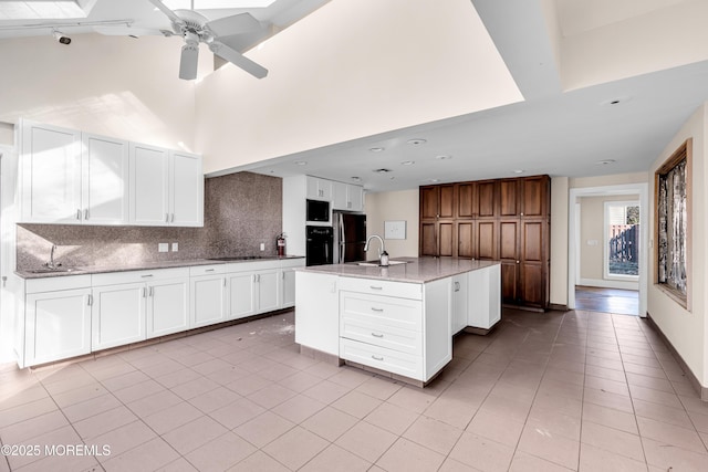 kitchen featuring white cabinets, decorative backsplash, freestanding refrigerator, a sink, and light tile patterned flooring