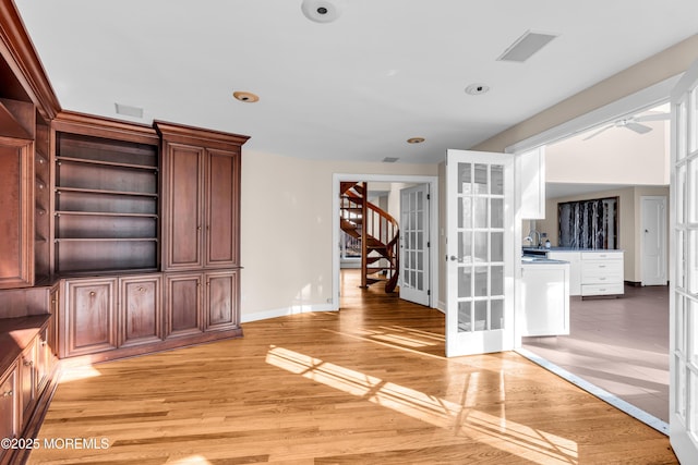 interior space with light wood-style flooring, visible vents, baseboards, french doors, and stairway