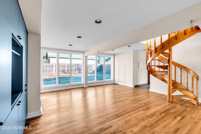 living room with light wood-style floors, plenty of natural light, stairway, and baseboards