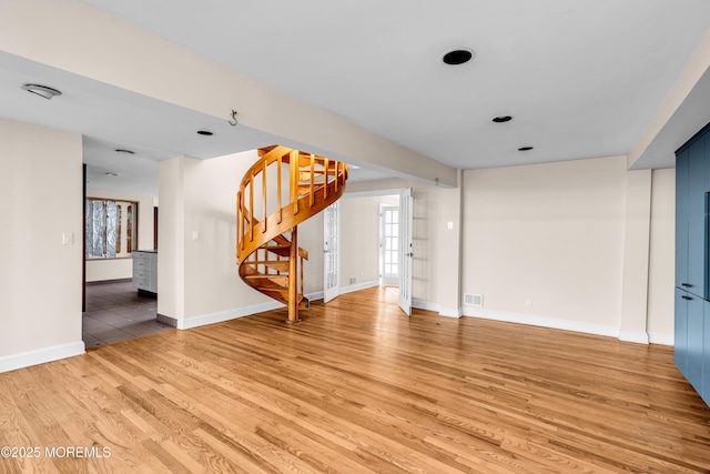 unfurnished living room with baseboards, stairway, visible vents, and light wood-style floors