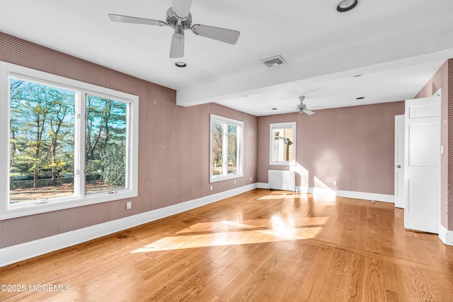 unfurnished room featuring radiator, visible vents, light wood-style floors, ceiling fan, and baseboards