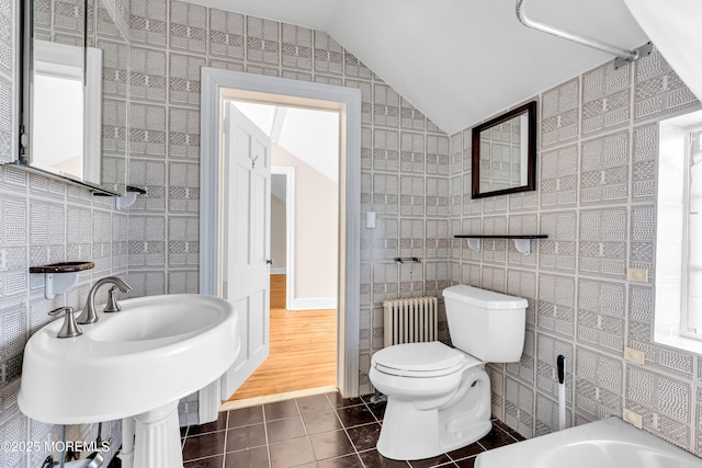 bathroom featuring lofted ceiling, toilet, radiator, tile patterned flooring, and tile walls