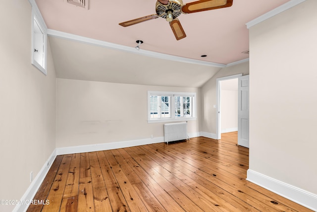 spare room with baseboards, radiator, lofted ceiling, ceiling fan, and hardwood / wood-style floors