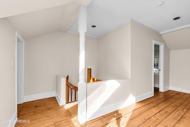 hallway featuring lofted ceiling, wood-type flooring, baseboards, and an upstairs landing