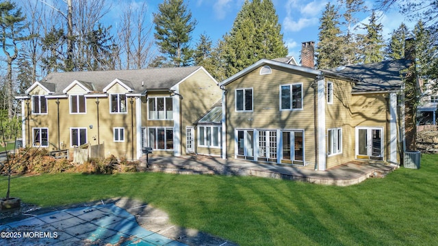 back of property with a chimney, a lawn, a patio, and french doors