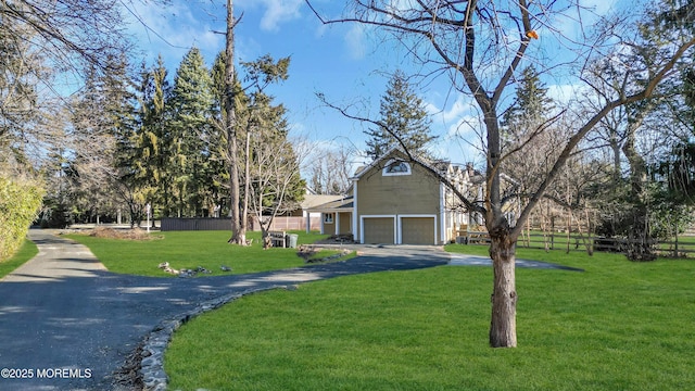 view of front of home featuring an outbuilding, driveway, fence, and a front yard