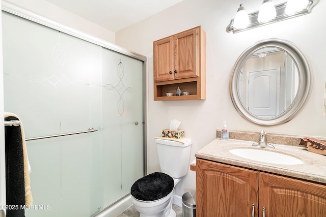 bathroom with a shower stall, toilet, and vanity