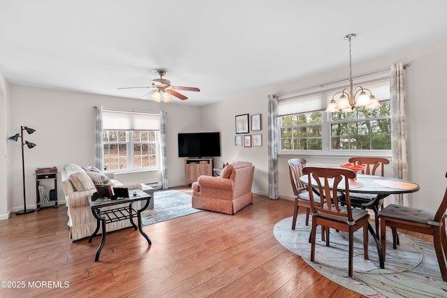 dining space with light wood-style floors, a wealth of natural light, baseboards, and ceiling fan with notable chandelier