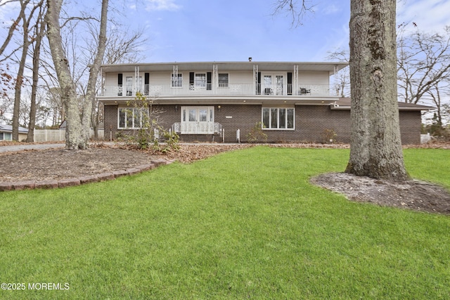 rear view of house with a balcony, a lawn, and brick siding