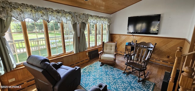 living area with wood ceiling, wood walls, a wainscoted wall, a baseboard heating unit, and a wealth of natural light
