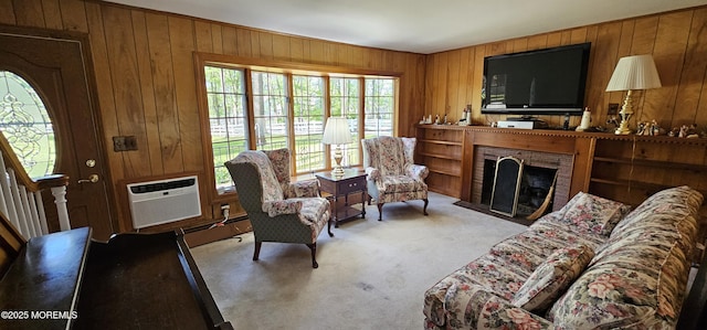 carpeted living area featuring wooden walls, an AC wall unit, and a brick fireplace