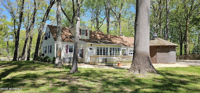 new england style home featuring a wooden deck and a front yard