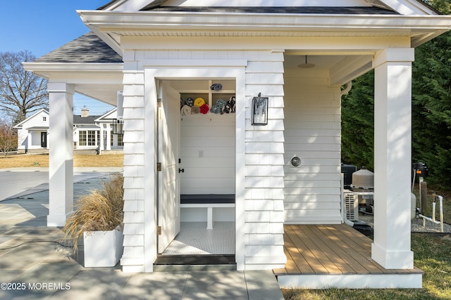 doorway to property featuring roof with shingles