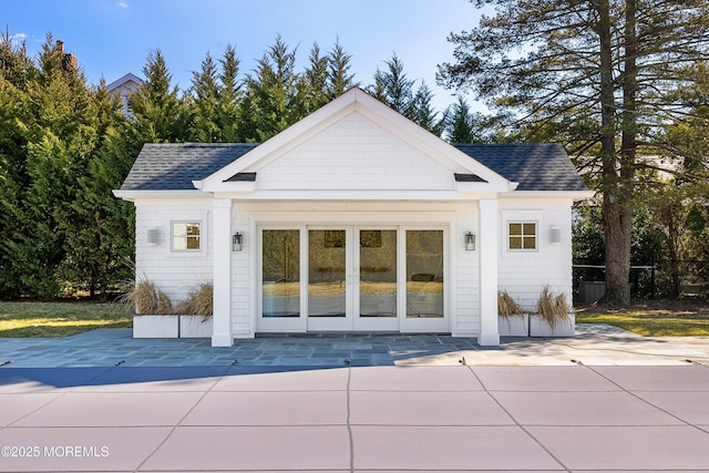 exterior space with a patio area, roof with shingles, and an outdoor structure