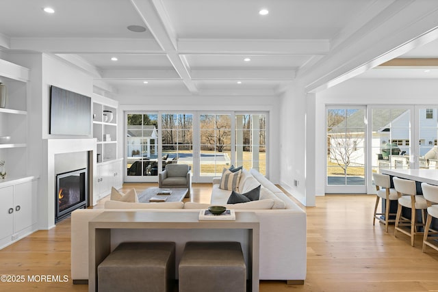 living area featuring a glass covered fireplace, beam ceiling, light wood-style flooring, and recessed lighting