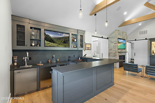 kitchen featuring a barn door, visible vents, dark countertops, beamed ceiling, and backsplash