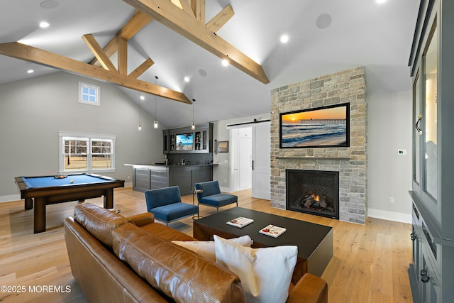 living room featuring light wood finished floors, a barn door, beamed ceiling, high vaulted ceiling, and indoor wet bar