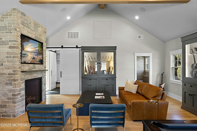 living room featuring light wood finished floors, a barn door, and visible vents