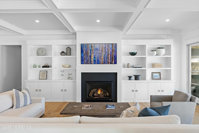 living room with light wood finished floors, a warm lit fireplace, coffered ceiling, and beam ceiling